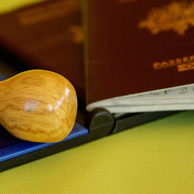 imagen de un sello de madera junto a una esponja de tinta y un pasaporte